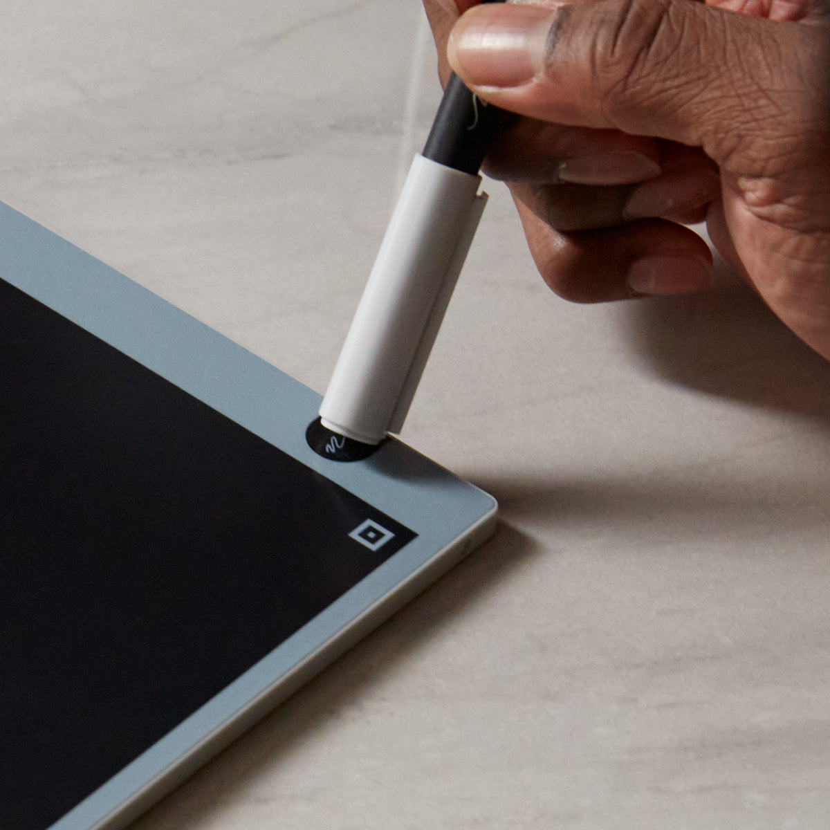 Image of someone erasing the board by touching the cap to the circle logo